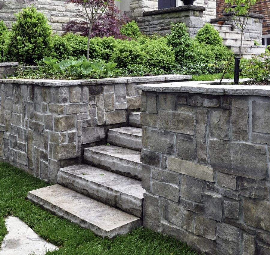 Luxury landscaping features a retaining wall and natural stone steps and stepping stones.